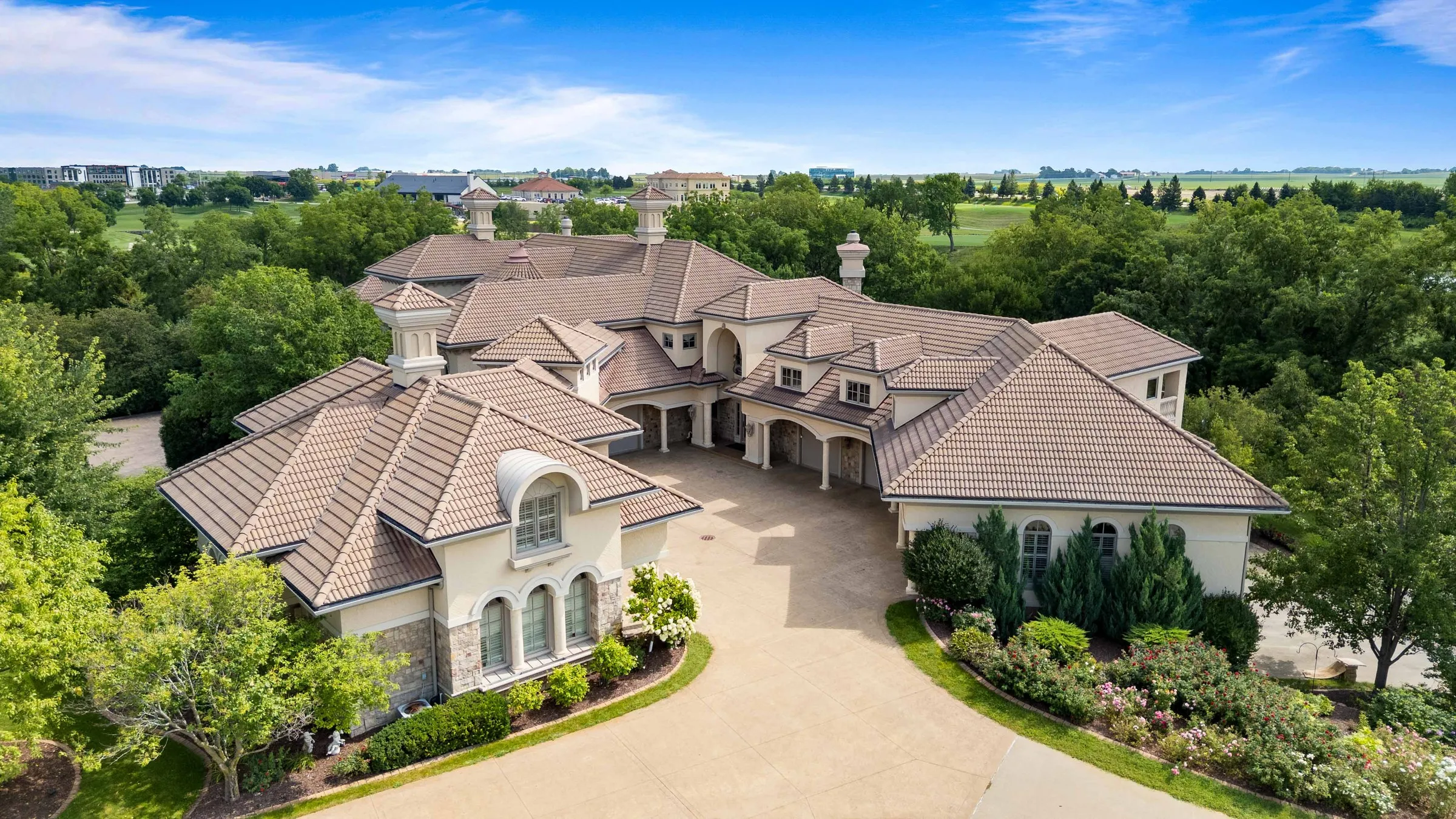 Aerial view of a large house with a tile roof and a circular driveway.